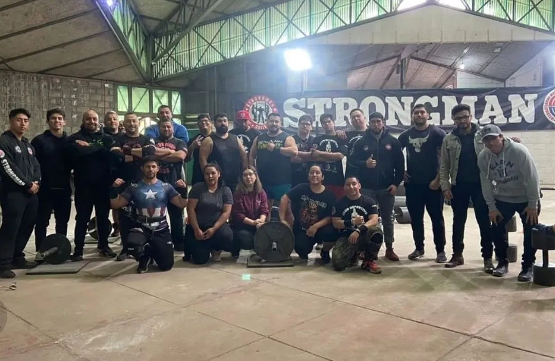Victor Yanac junto a un grupo de atletas de strongman en un gimnasio